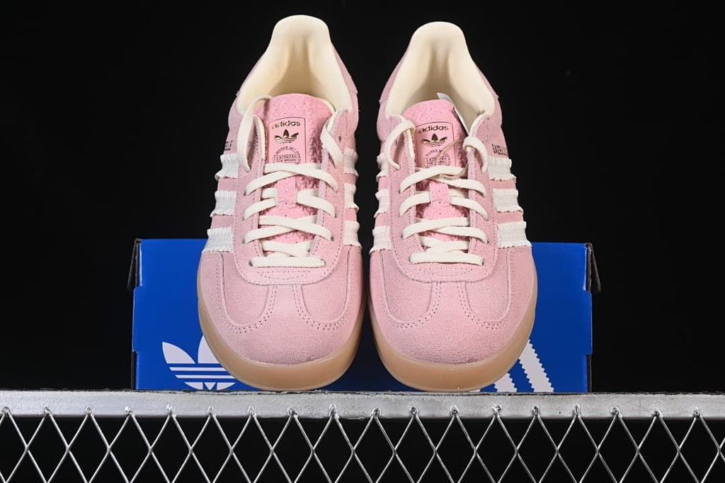 Front view of the pink sneaker pair displayed on the blue shoebox