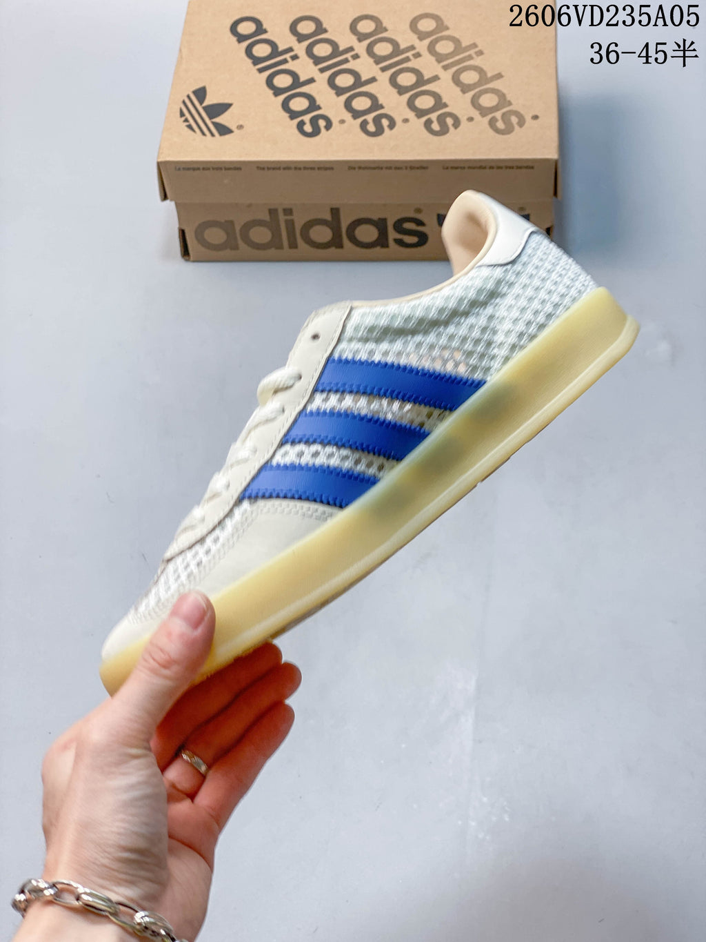 Side profile of a white and light grey low-top sneaker with blue stripes