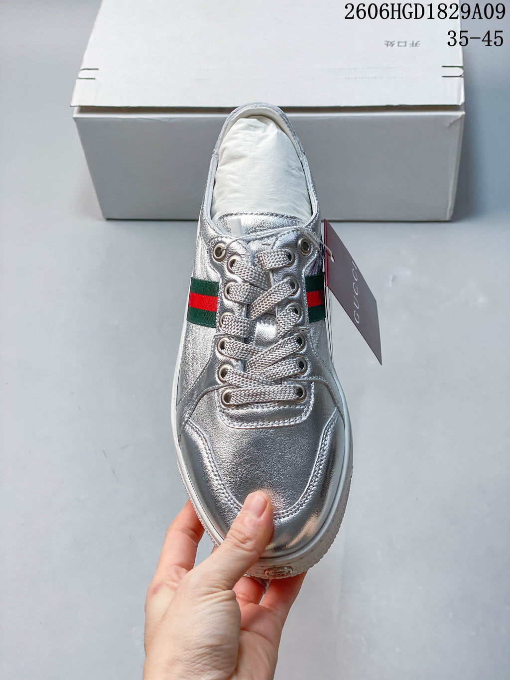 Front view of a silver lace-up sneaker with a green-and-red side stripe.