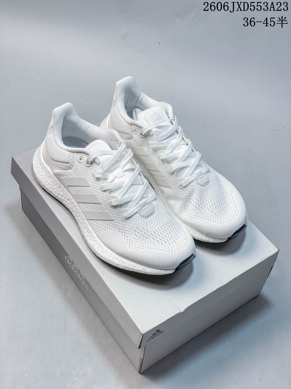 Pair of white Adidas PureBoost 21 running shoes on a shoebox