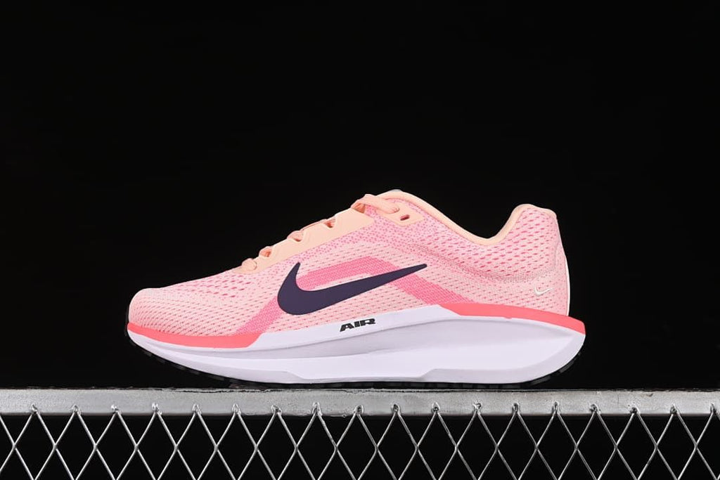 Side view of pink Nike Winflo 11 running shoe with dark Swoosh and light midsole.