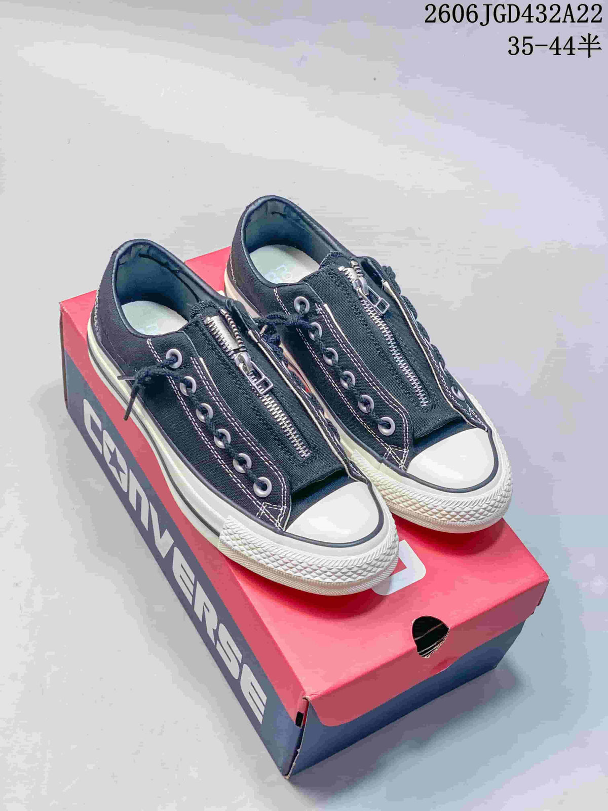 Black low-top Converse sneakers with front zippers, white toe caps, and off-white soles