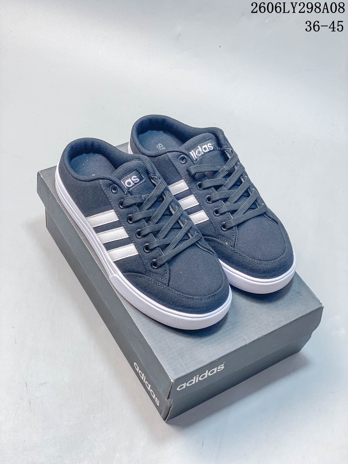 Navy adidas mule sneakers with white side stripes, shown on a shoe box.
