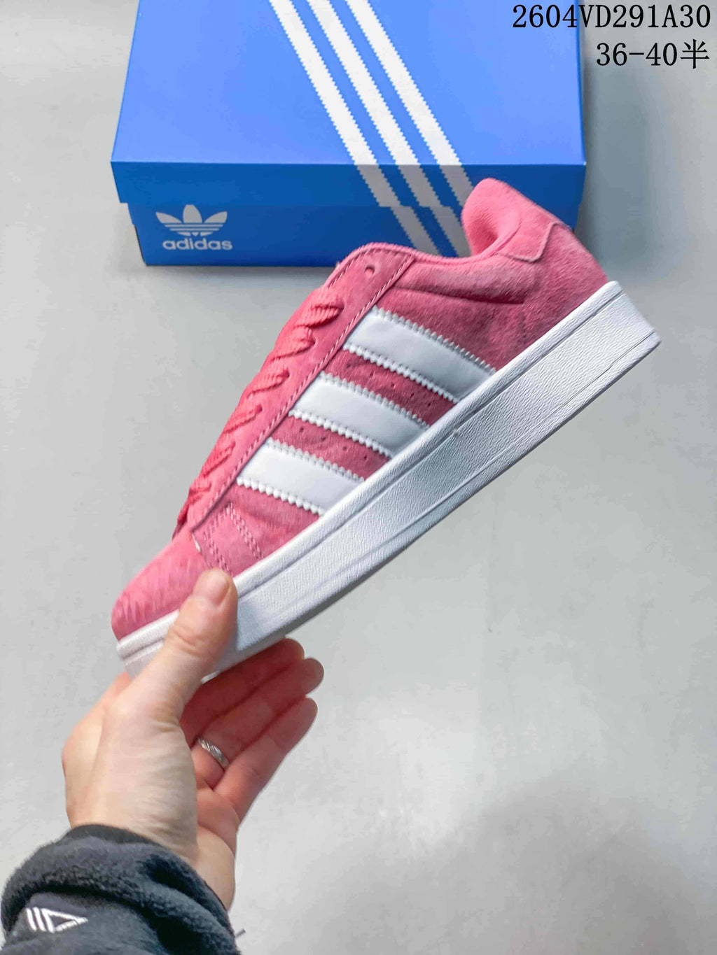 Side view of the pink low-top sneaker with three white stripes and a white sole.