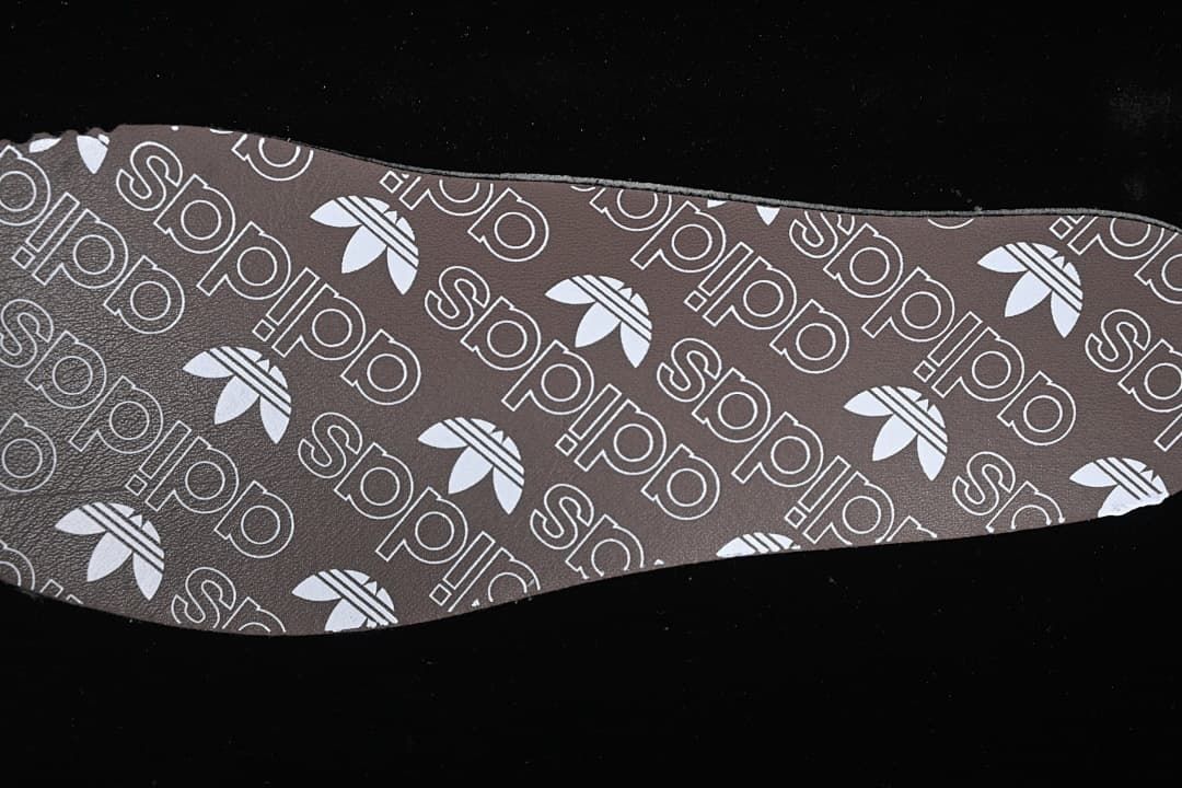Brown shoe insole with repeating adidas branding and trefoil motifs