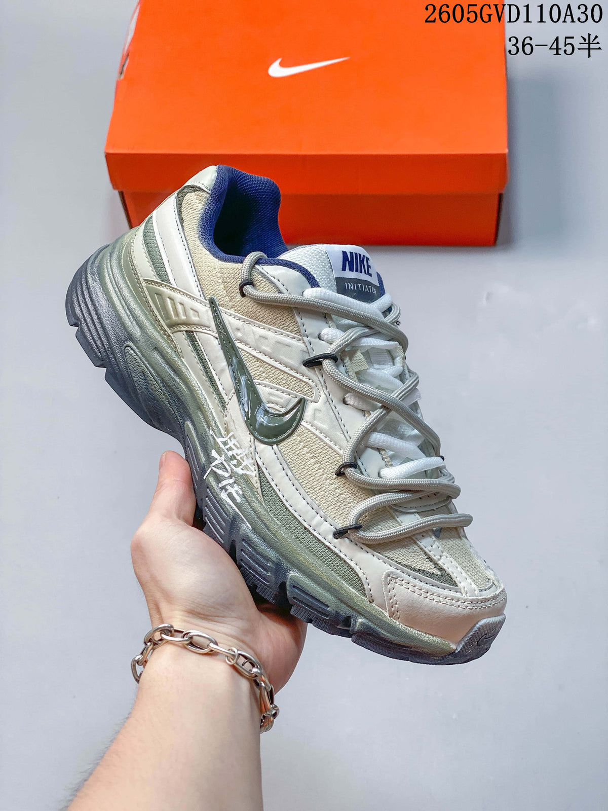 Angled side view of a Nike Initiator sneaker in cream, silver tones and blue