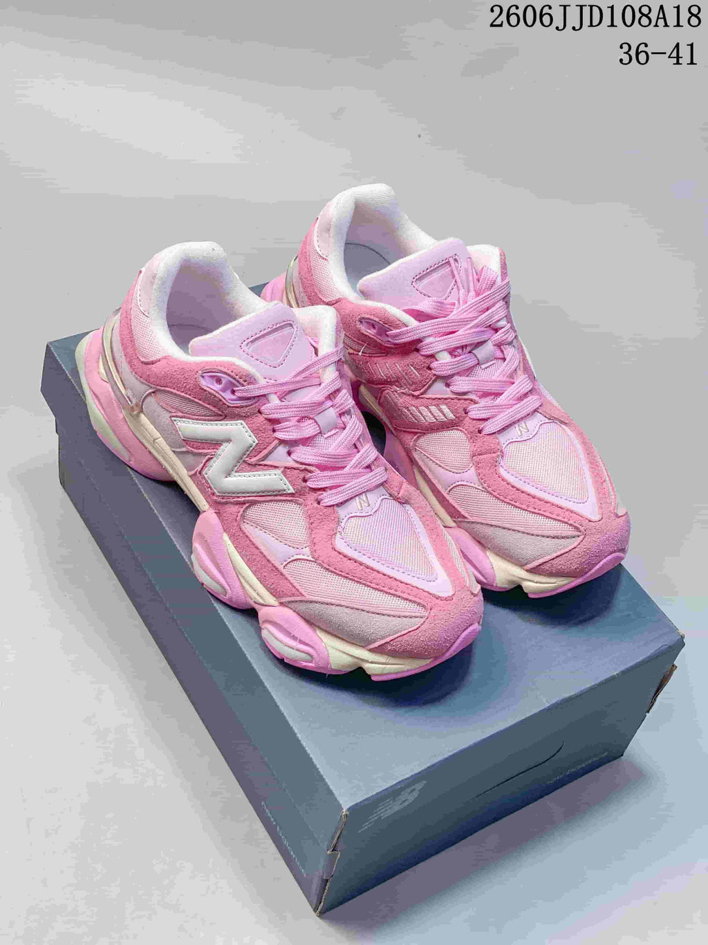 Pair of pink New Balance 9060 sneakers displayed on a shoebox