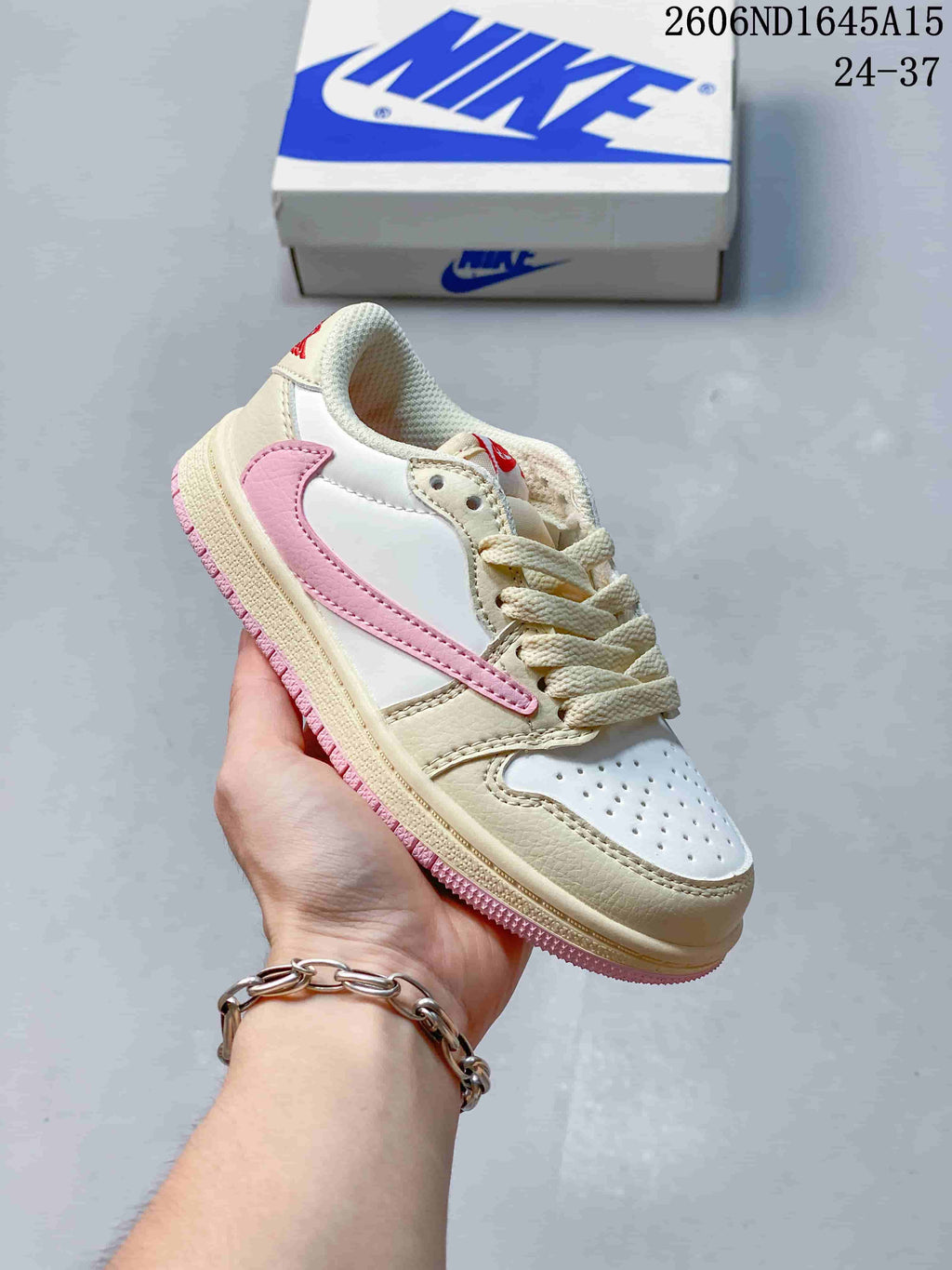 Side view of a white and beige kids’ low-top sneaker with a pink side detail and pink outsole.