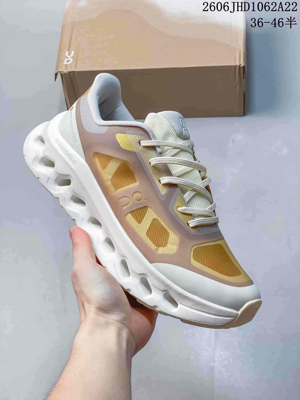 Side view of beige and gold On Cloudtilt Remix sneakers with a sculpted sole.