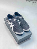 Pair of charcoal Onitsuka Tiger slip-on sneakers with white side stripes, shown on a branded box