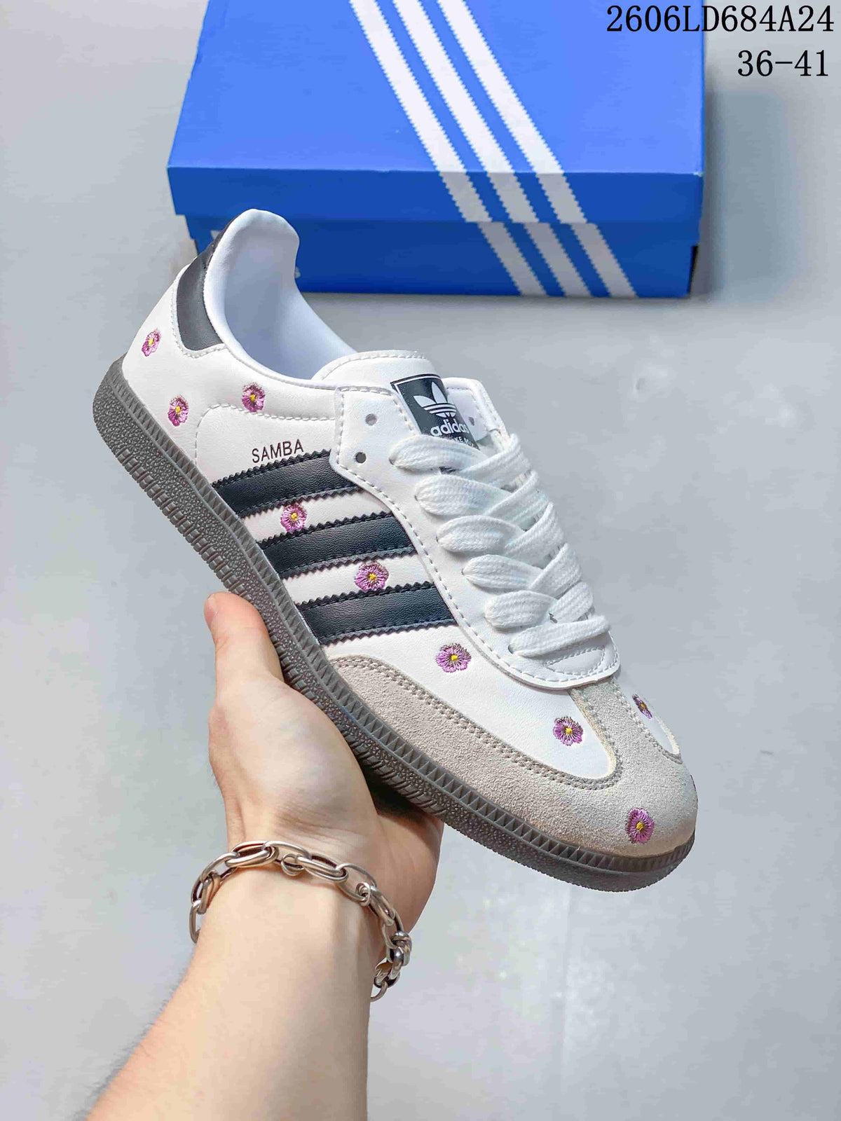 White Adidas Samba sneaker with purple floral details and dark side stripes.