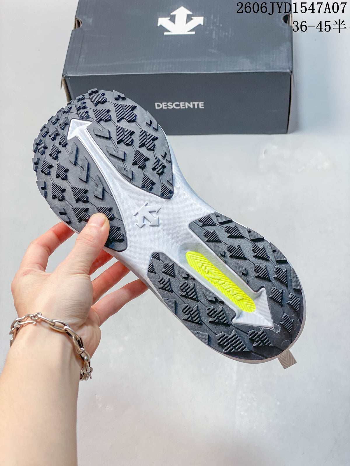 Underside of a DESCENTE shoe showing its dark patterned outsole and a light-colored central section.