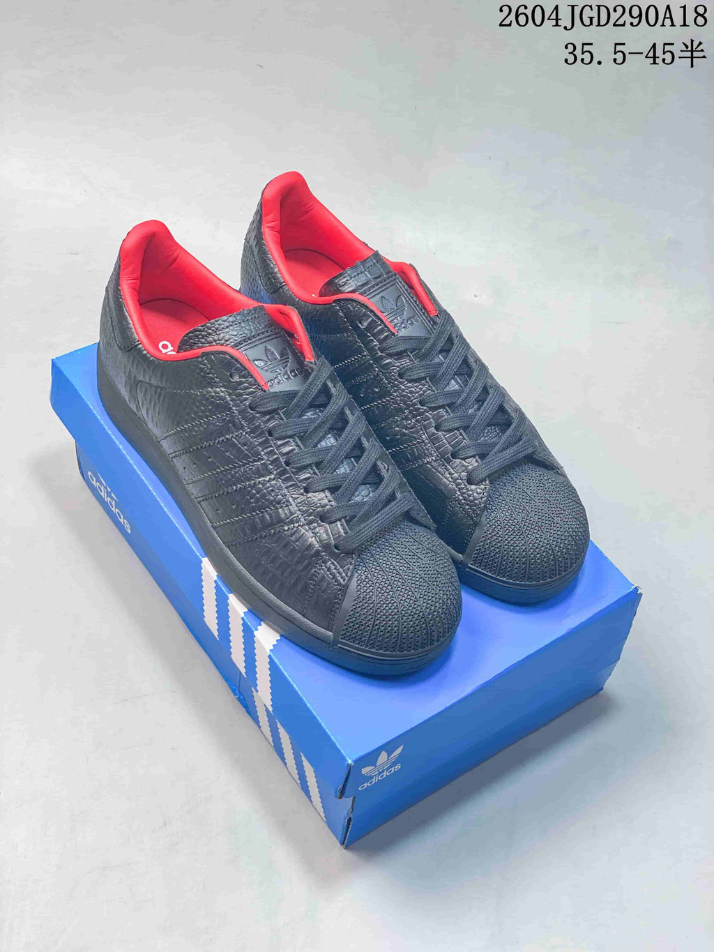 Pair of black Adidas Originals Superstar 2 sneakers with textured uppers, shell toes and red collar lining
