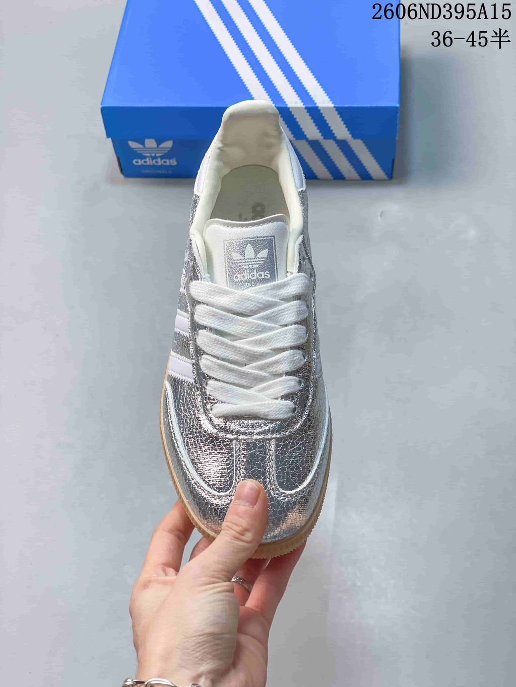 Top view of a silver Adidas Originals sneaker with white laces and stripes