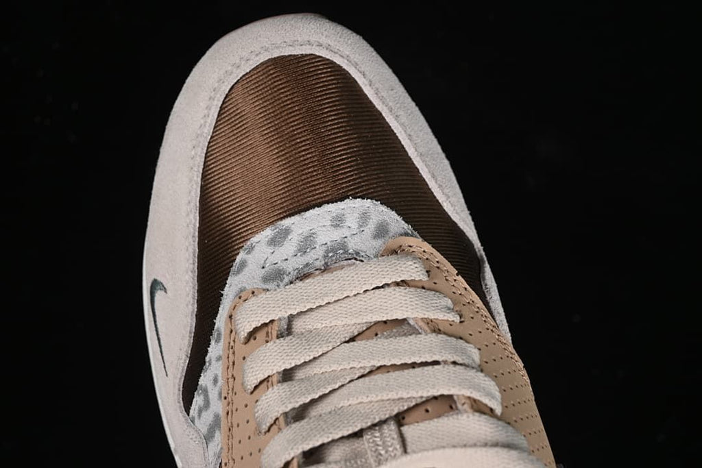 Top-down view of the brown toe panel, patterned overlay, and cream laces