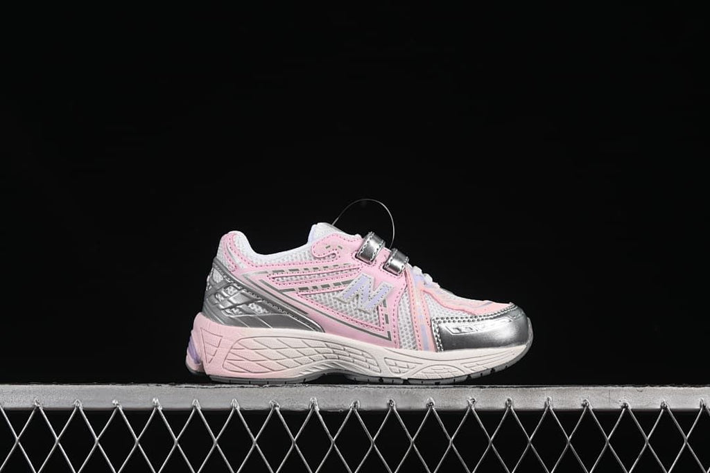 Side profile of a pink and silver kids’ sneaker with two fastening straps.