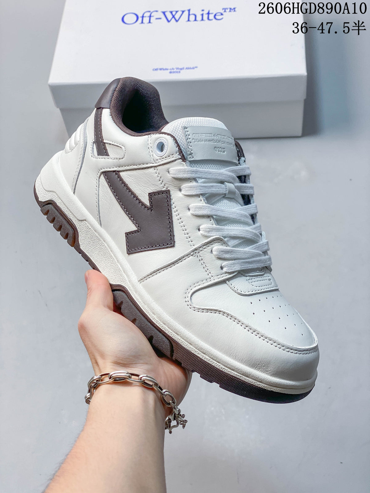 Angled view of a white low-top sneaker with brown Arrow-style side detail and outsole.