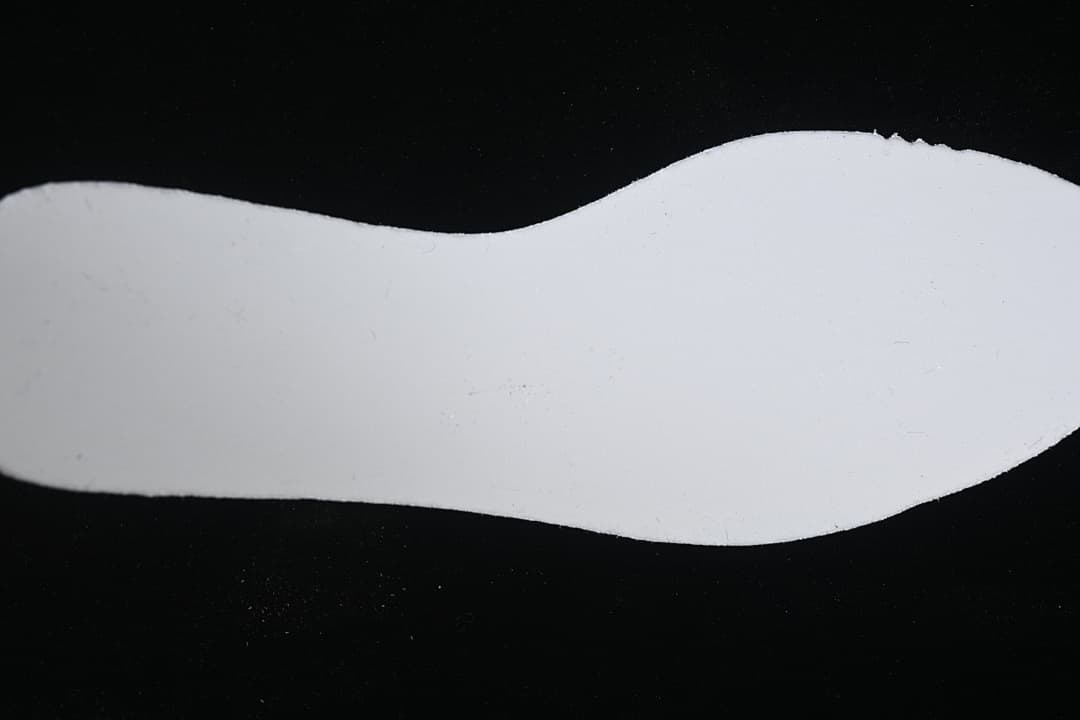 Plain white shoe-shaped insert photographed against a black background.