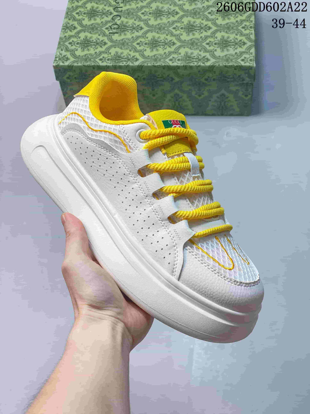Side view of a white sneaker with perforated panels, textured upper, thick sole, and yellow accents.