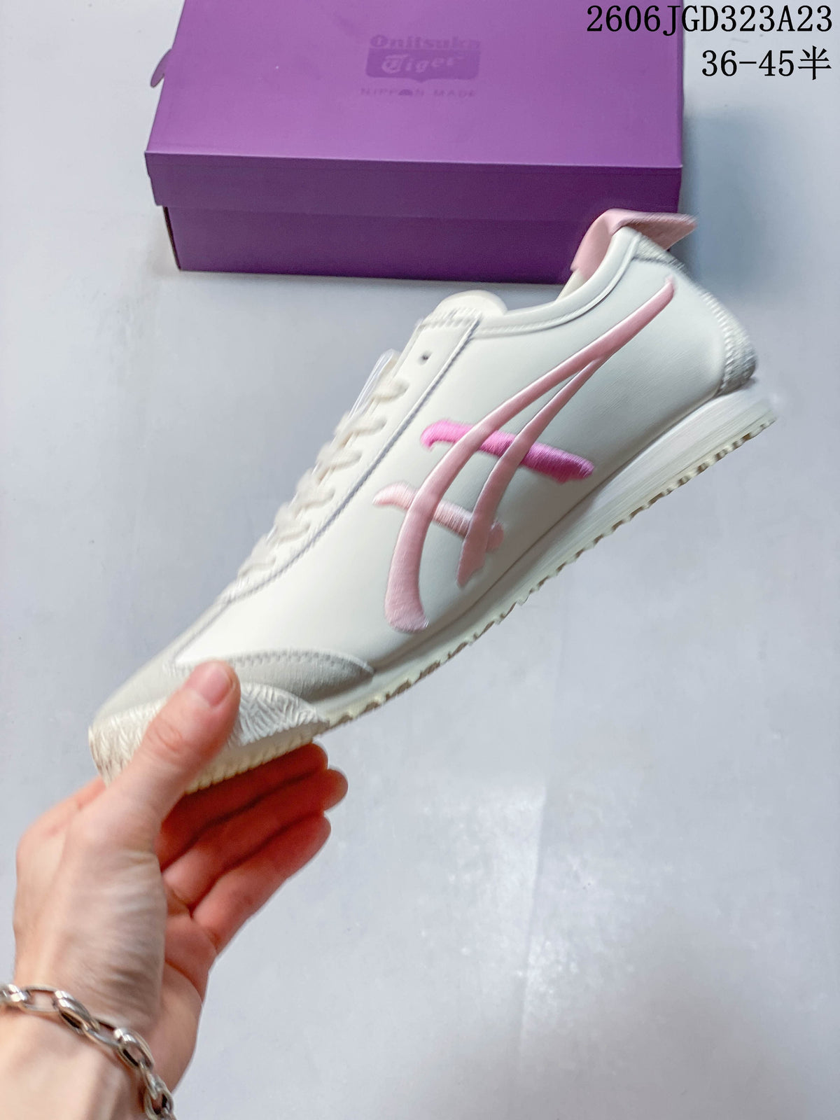 Side view of a cream sneaker with pink side detailing.