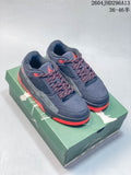 Pair of navy Jordan low-top sneakers with gray panels and red accents, shown on a green shoe box.