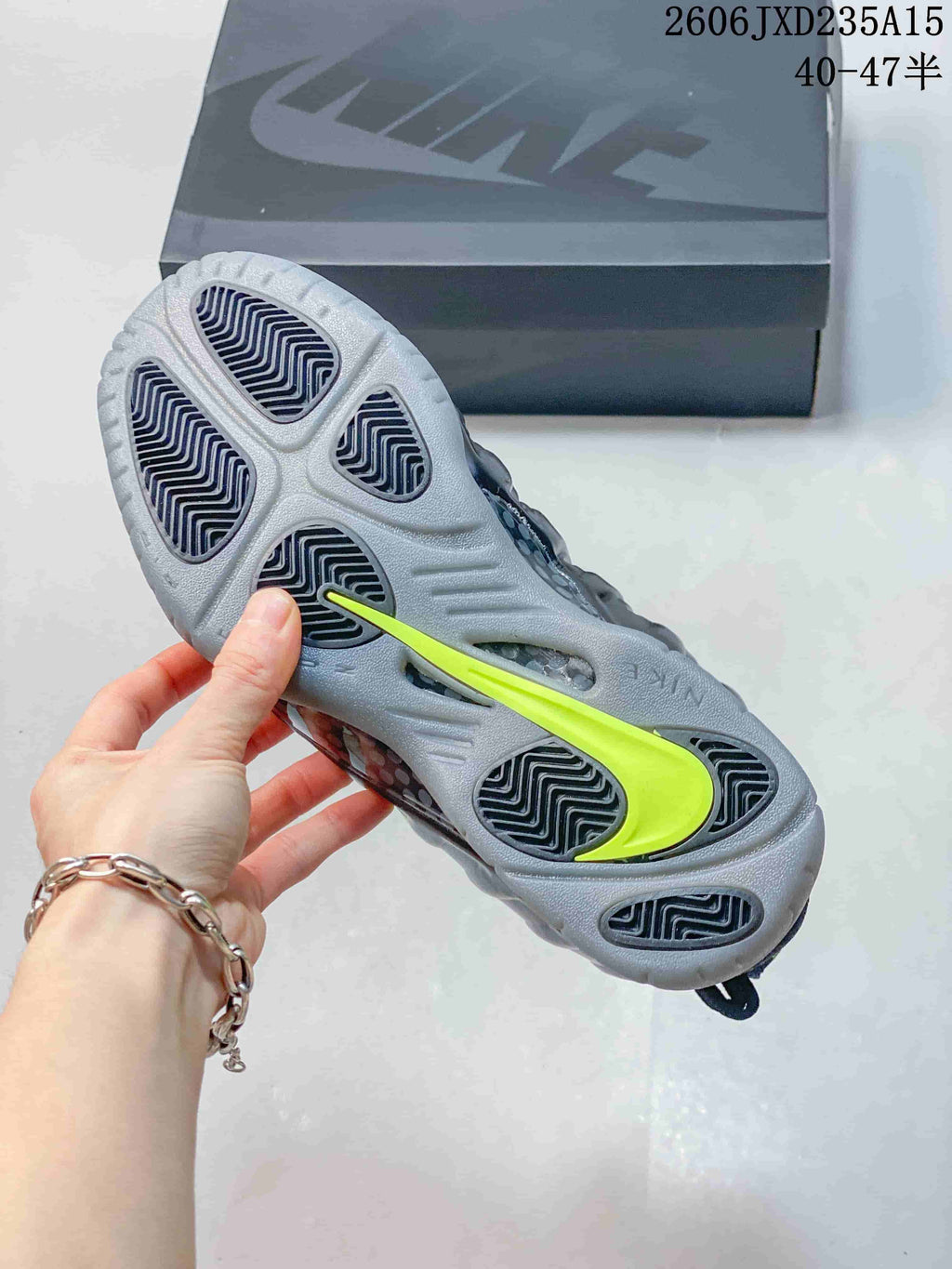 View of the gray outsole with dark traction sections and a bright green Nike-shaped detail.