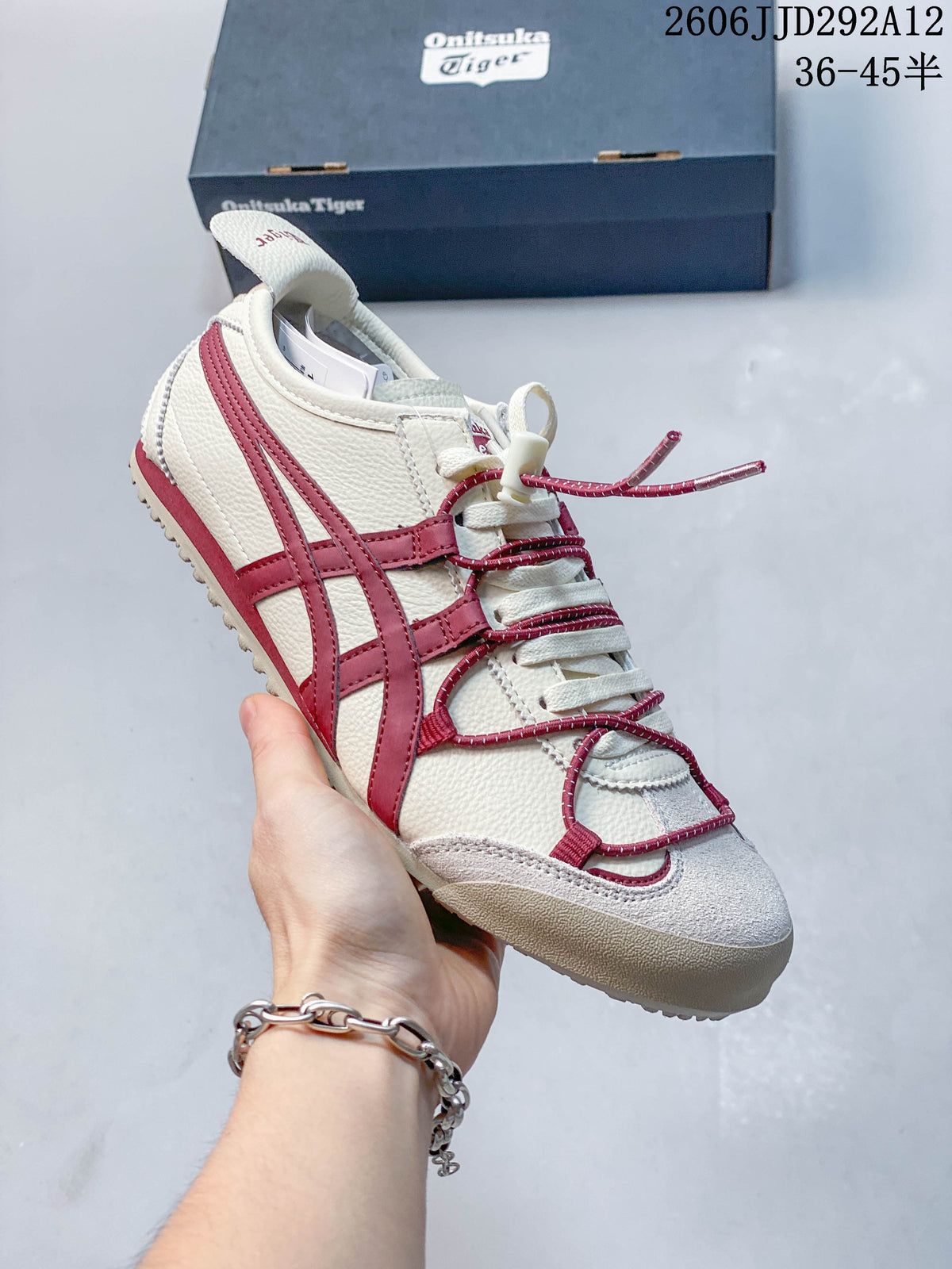 Side view of a white Onitsuka Tiger Mexico 66 Deluxe sneaker with burgundy accents and cord details.