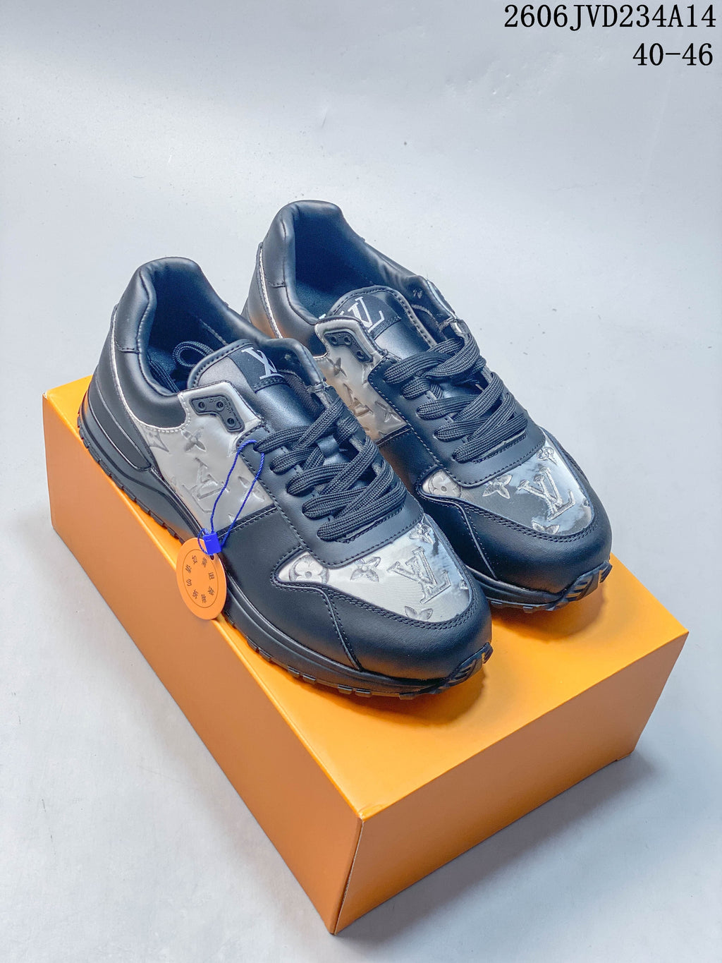 Pair of dark gray Louis Vuitton Run Away low-top sneakers with patterned panels and lace-up fronts, displayed on an orange box