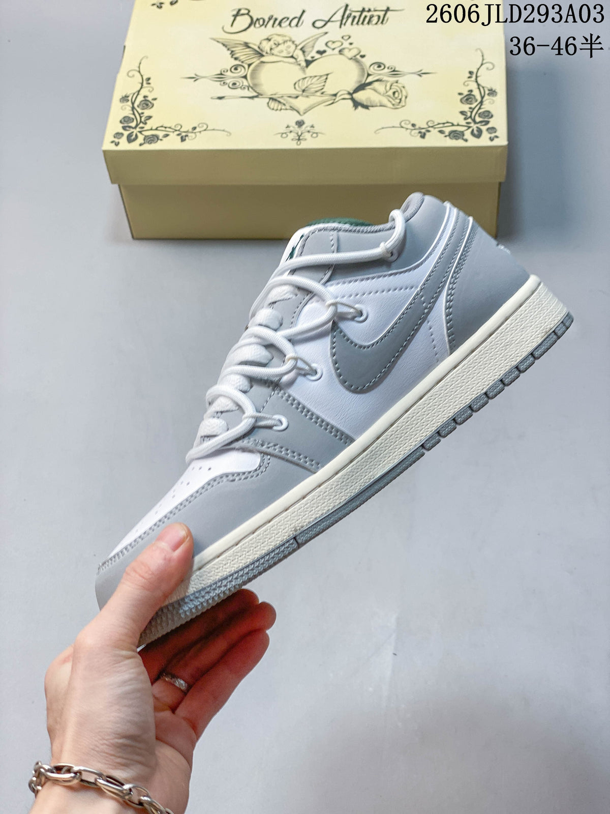 Side view of a white and gray Jordan low-top sneaker with a gray side logo and patterned panels; overlay shows a size range.