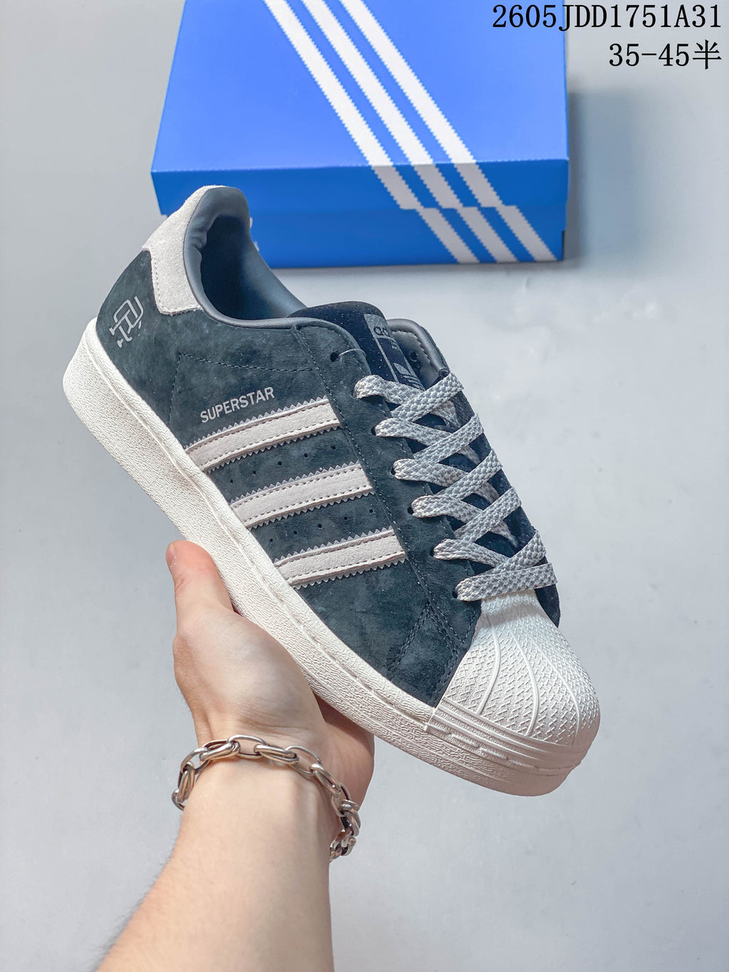 Dark suede-look sneaker with pale stripes, a white shell toe and light sole