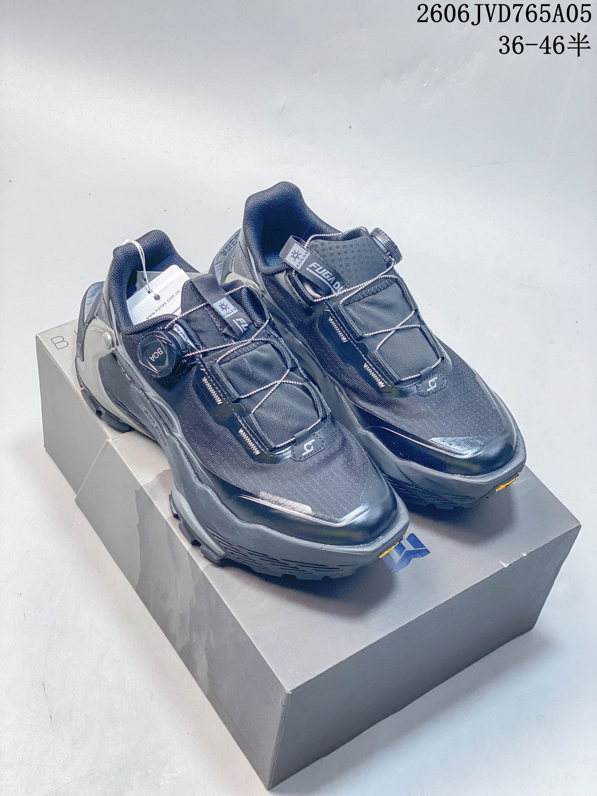 Pair of dark gray Kailas FUGA EX3 BOA trail shoes on a box, showing their dial closures and mesh-style uppers.