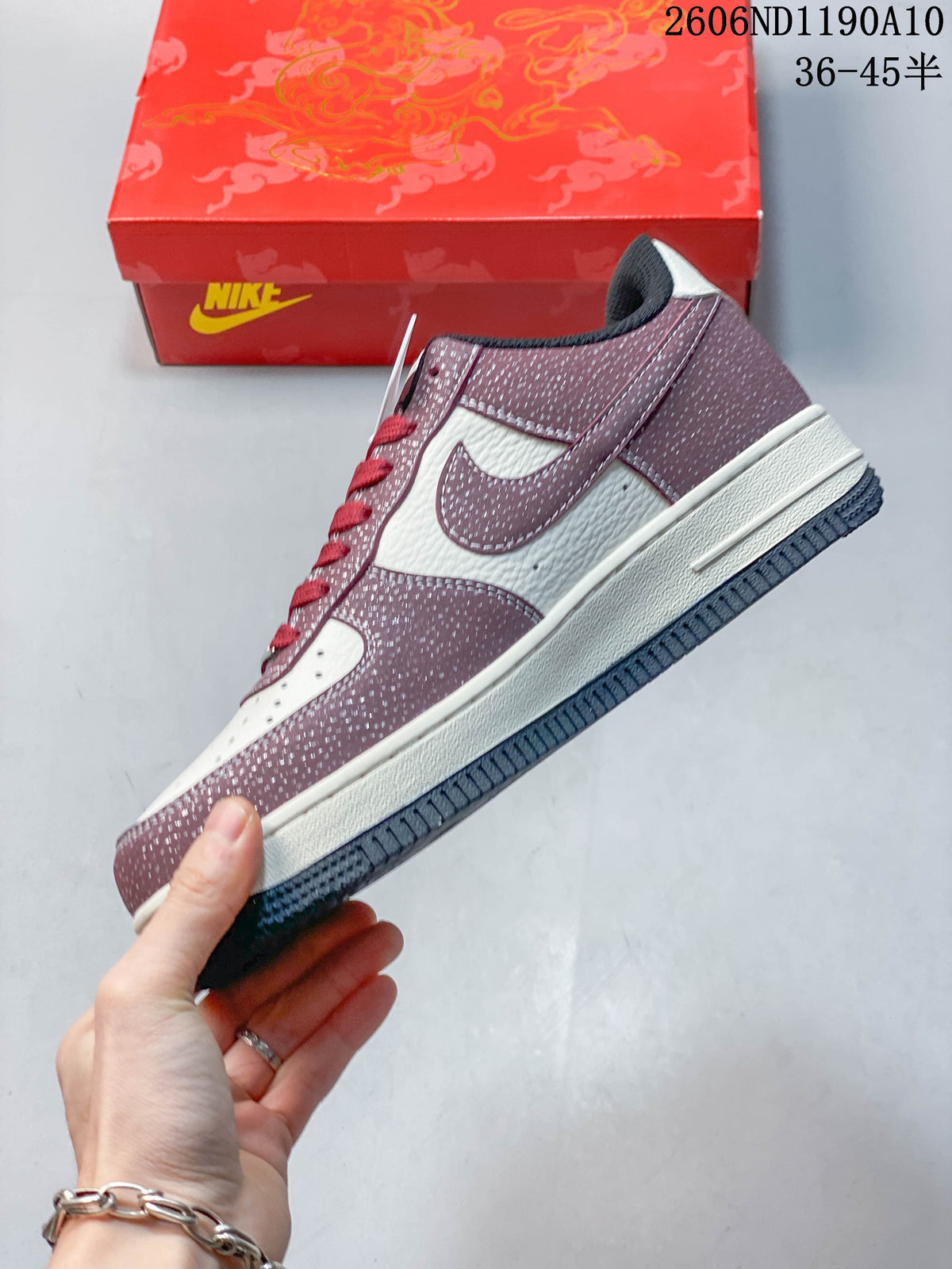 Side view of a low-top sneaker with burgundy patterned panels, off-white sections, and a dark outsole