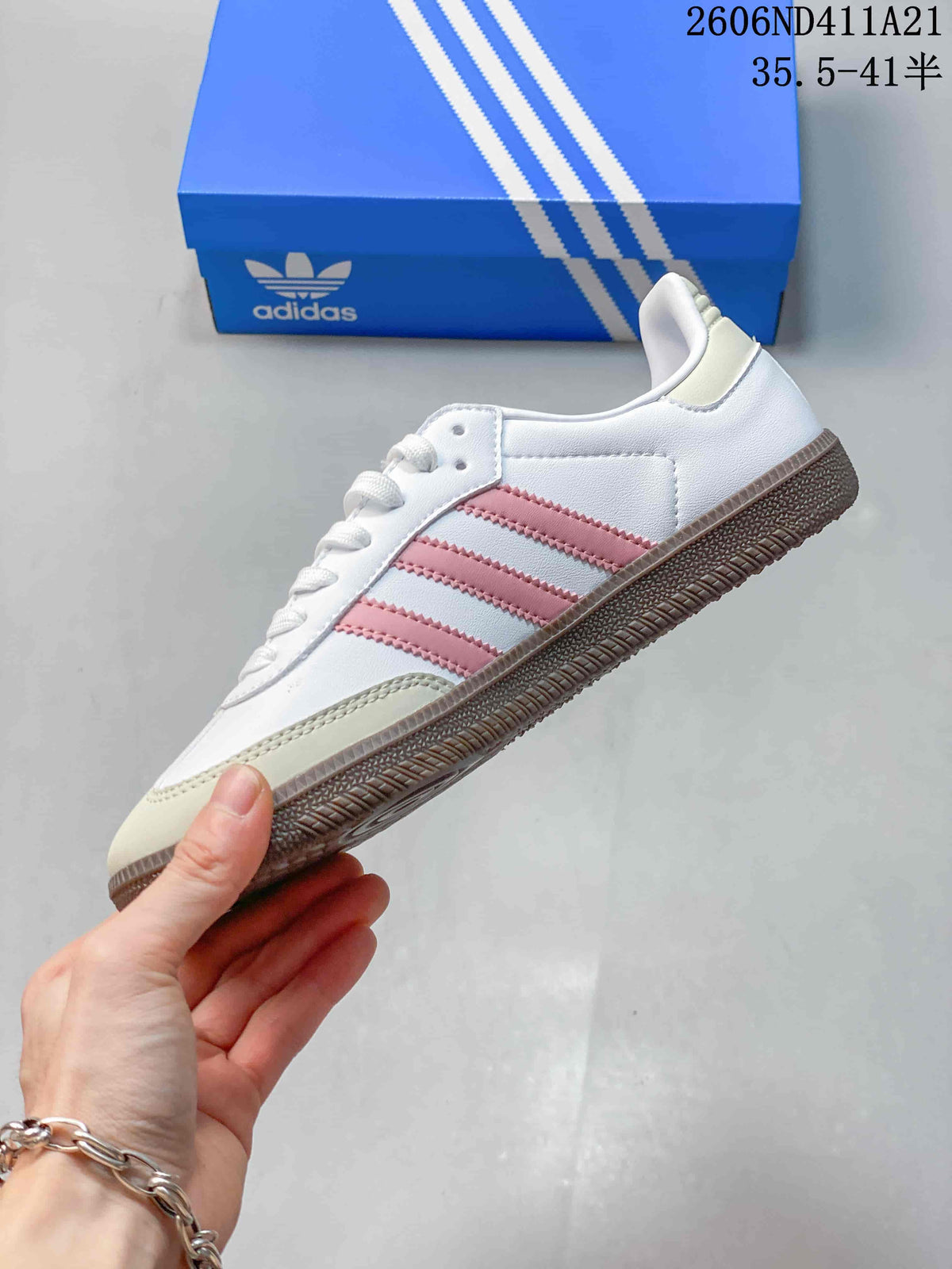 Side view of a white sneaker with pink stripes and a brown-toned outsole