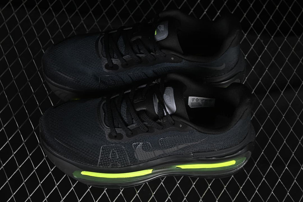 Pair of black running shoes with bright volt accents, photographed on a metal mesh platform.