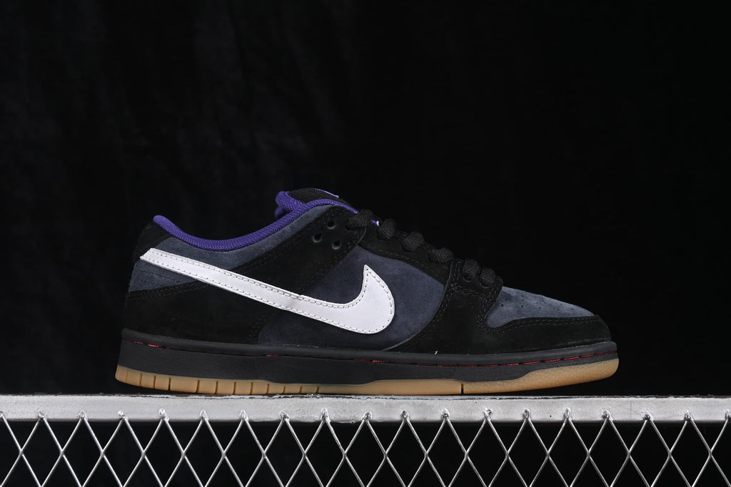 Side profile of a Nike SB Dunk Low sneaker highlighting the black, navy, and white color blocking.