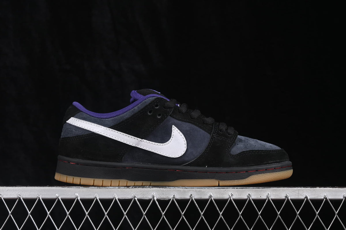 Side profile of a Nike SB Dunk Low sneaker highlighting the black, navy, and white color blocking.