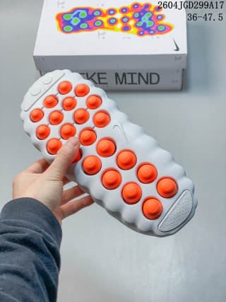 Underside of the white slide showing multiple orange circular outsole elements and raised tread sections.