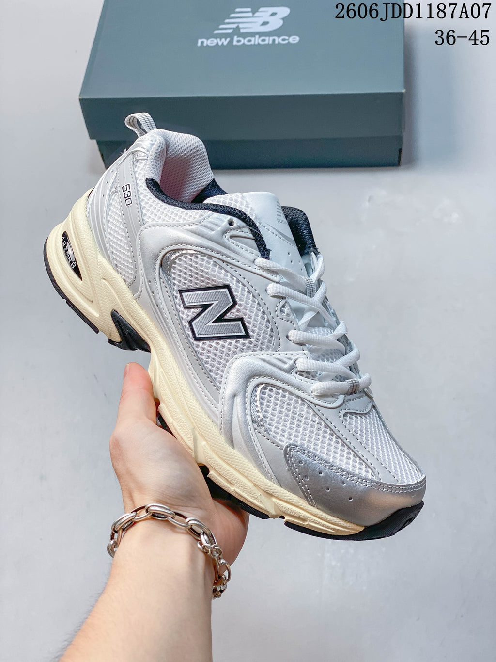 Angled side view of a white and grey New Balance 530 sneaker with dark accents