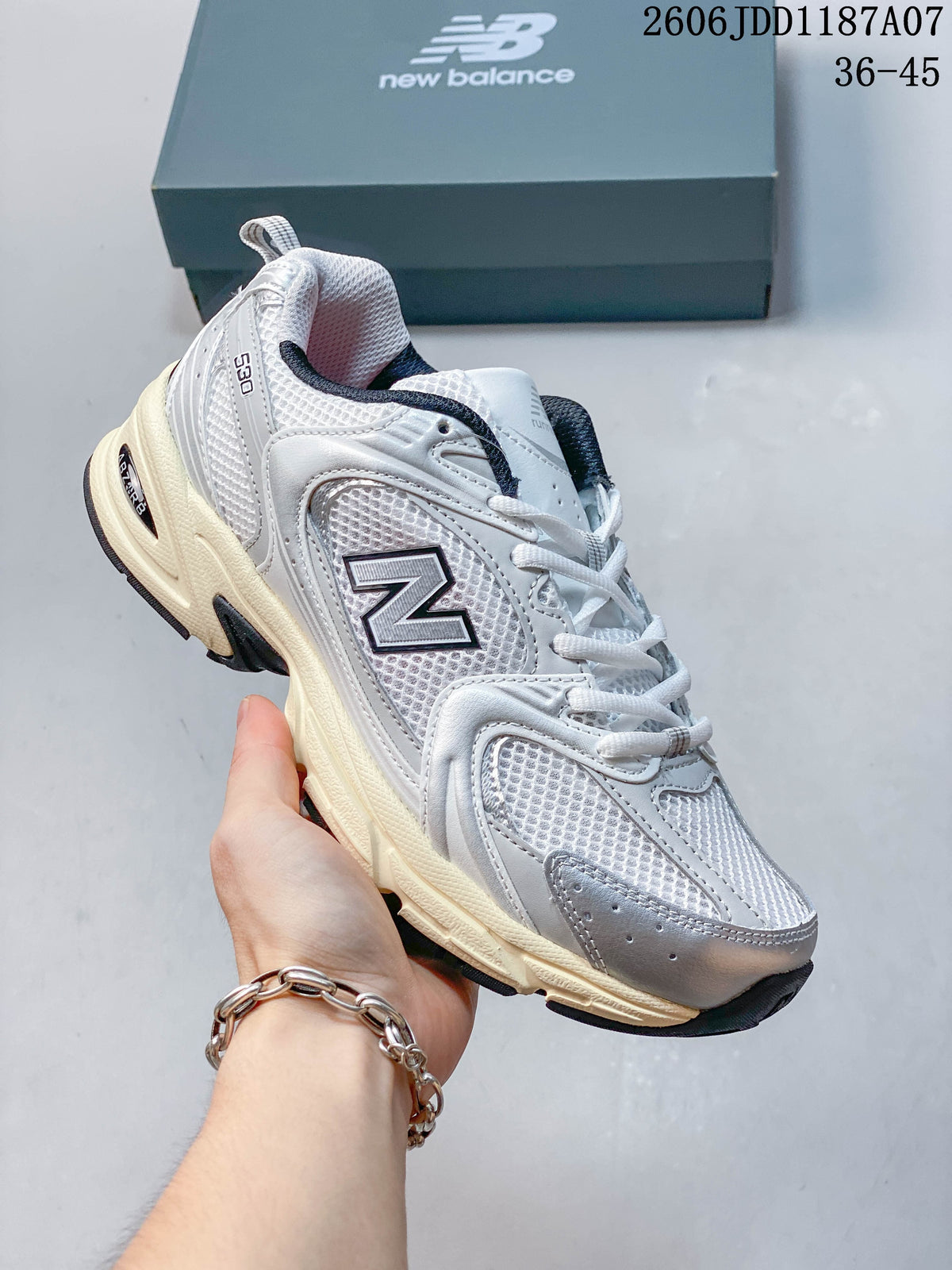 Angled side view of a white and grey New Balance 530 sneaker with dark accents