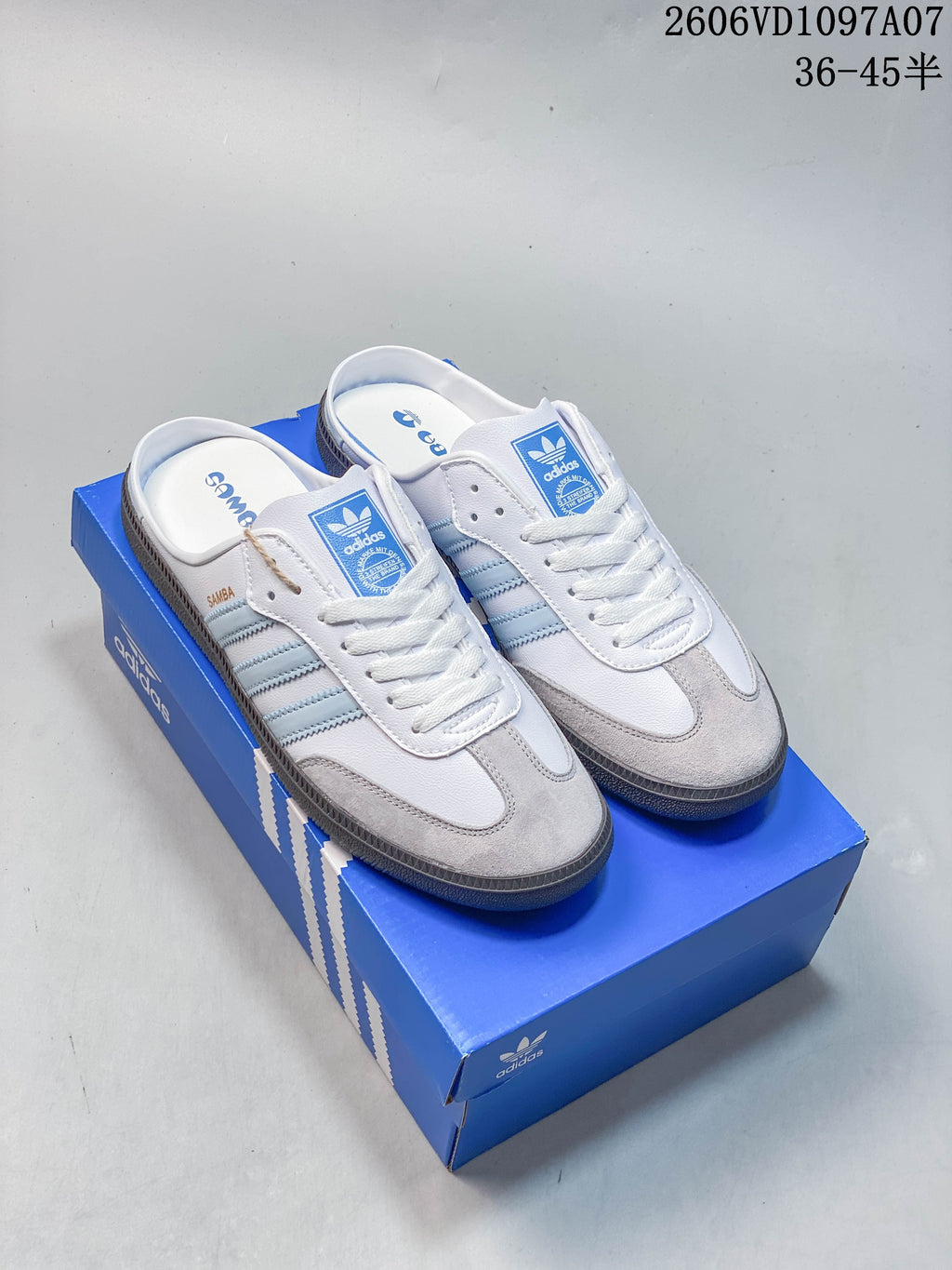Pair of white and light blue adidas Samba OG mule sneakers with gray toe overlays and open backs