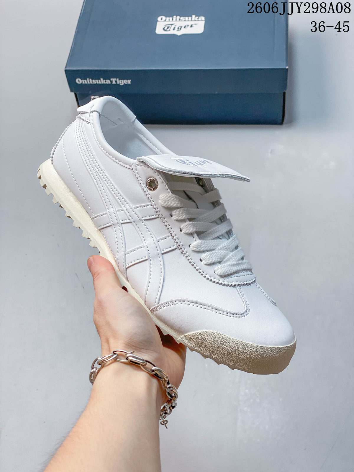 White Onitsuka Tiger Mexico 66 Golf low-top sneaker with a lugged outsole beside a branded box.