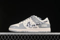 Side view of a light gray and off-white Nike SB Dunk Low with patterned graphics and printed lettering.