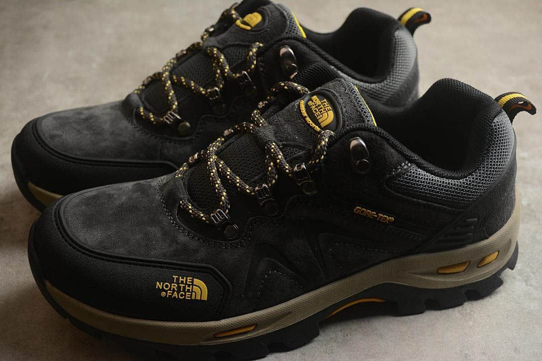 Pair of black and yellow low-cut hiking shoes shown from the side.