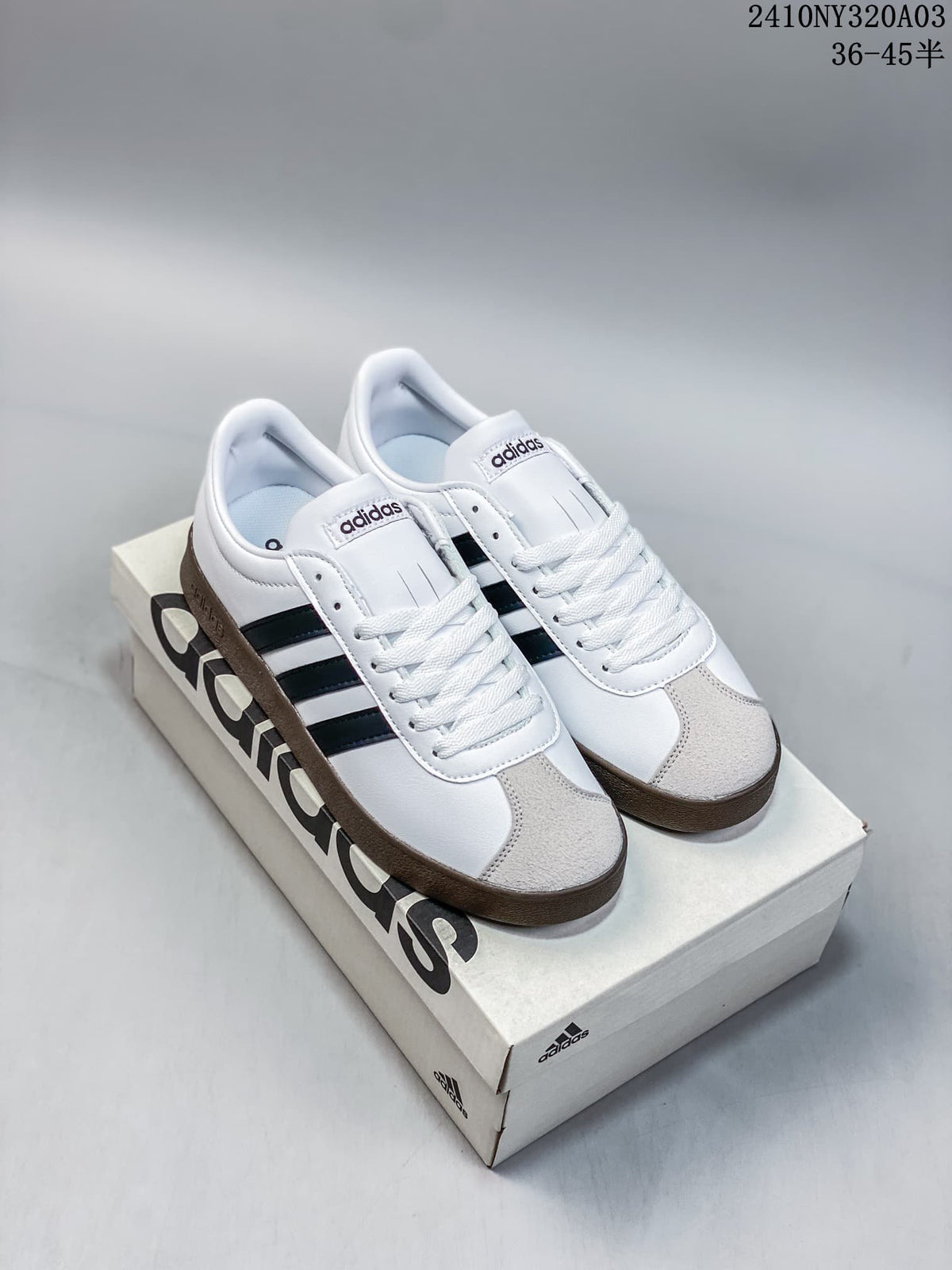 Pair of white Adidas VL Court 2.0 sneakers with black side stripes, light gray toe overlays, and dark gum-colored soles on a shoe box.