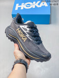 Dark gray Hoka Mafate Speed 2 shoe with gold accents, shown with a blue shoe box.