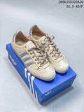 Pair of beige adidas Originals Japan sneakers with silver stripes, shown on a blue shoebox