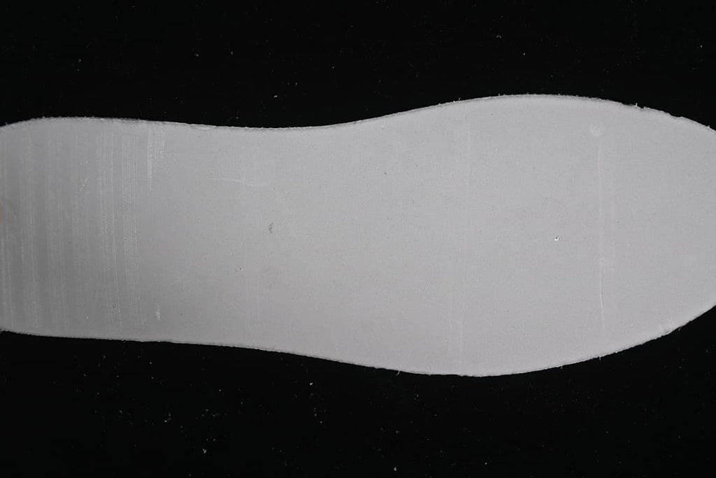 Plain white shoe insole shown on a dark background
