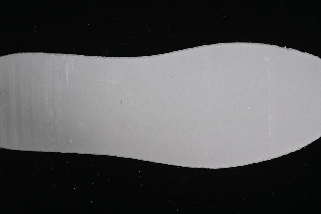 Plain white shoe insole shown on a dark background