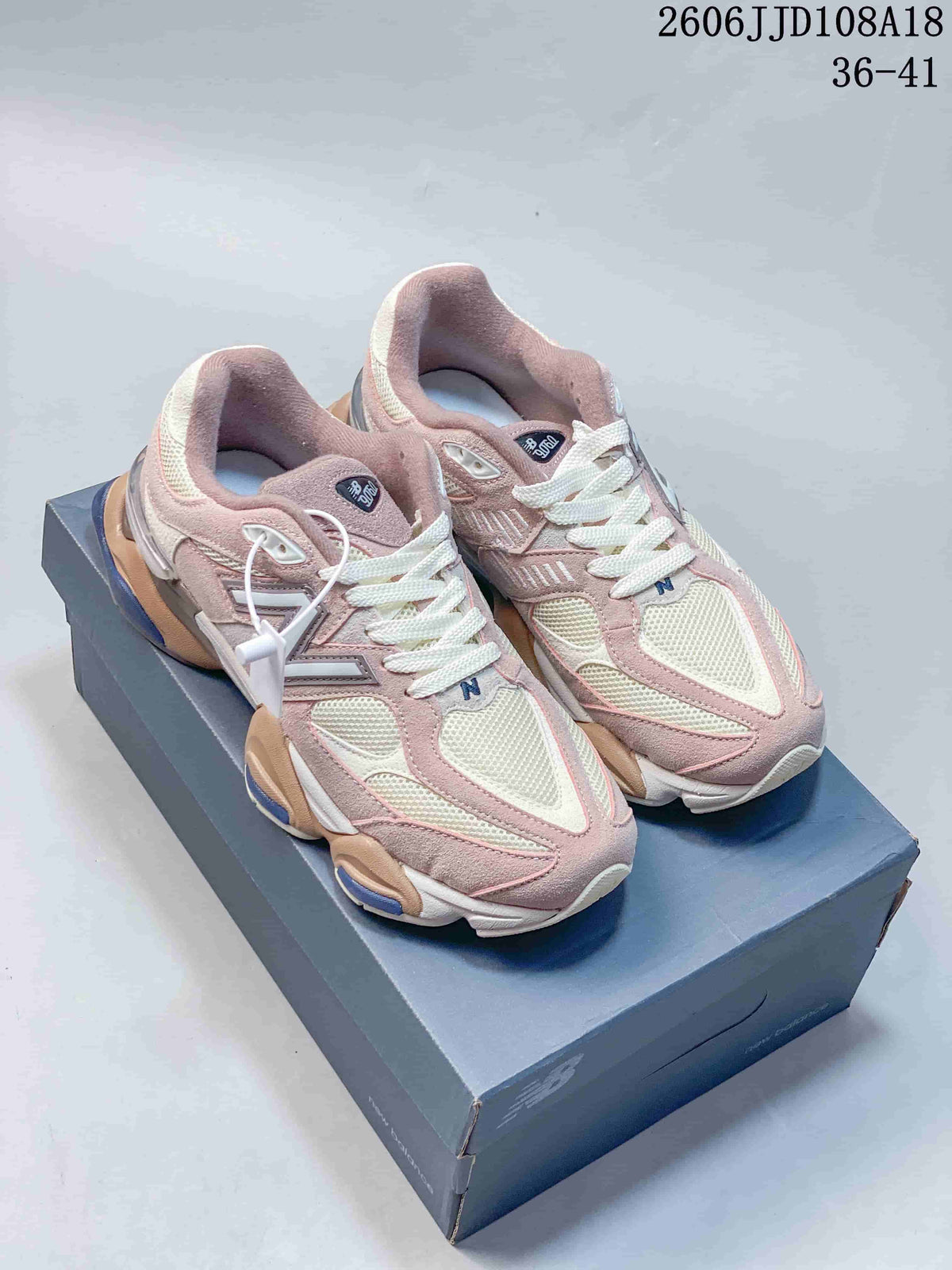 Pair of pink and cream New Balance 9060 sneakers on a shoebox