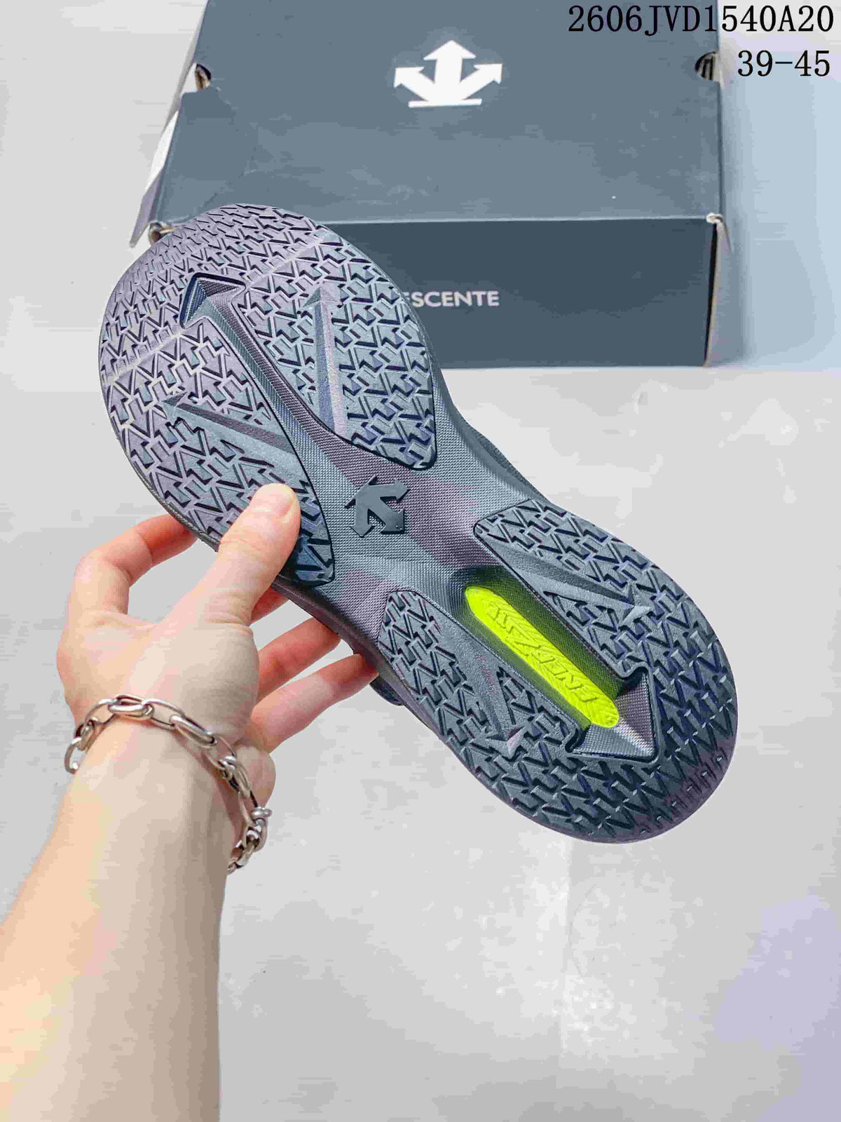 Close-up of the patterned outsole on a charcoal gray Descente sneaker